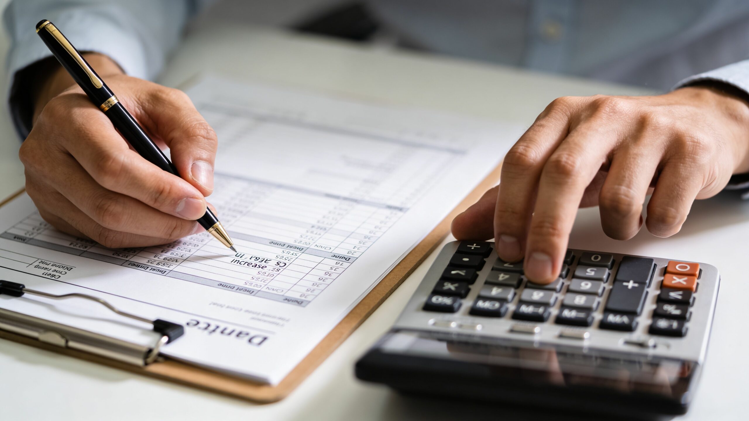 Un comptable travaillant sur une augmentation de loyer avec des documents, un stylo et une calculatrice.